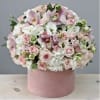 Pink and white flower arrangement in a round pink box