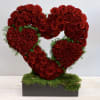 Heart-shaped arrangement of red roses on a moss-covered base