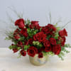 Red roses arranged in a gold vase with airy greenery