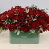 Dense red rose arrangement in a green rectangular vase