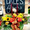 Autumn floral arrangement with sunflowers, roses, and candles in a white container
