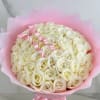 Bouquet of cream roses wrapped in pink paper with a pink ribbon