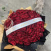 Large bouquet of red roses wrapped in black and gold paper with a white ribbon