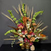Large tropical bouquet with orchids, roses, and wheat-like stems in a gold vase