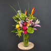 Tropical bouquet in a clear glass vase with pink, yellow, and white blooms