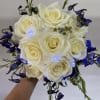Handheld bouquet of white roses with blue flowers and small lights
