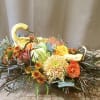 Low autumn centerpiece with gourd swans and orange and yellow flowers in an oval arrangement