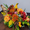 Autumn centerpiece with orange roses, mums, red flowers and gourds in a woven cornucopia