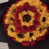 Round bouquet of red roses and yellow sunflowers wrapped in black paper