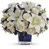 White lilies and roses arranged in a blue glass vase