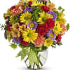 Colorful mixed bouquet in a clear glass vase with a green polka-dot ribbon