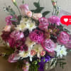 Pink and white mixed flower arrangement in a woven basket with a purple ribbon