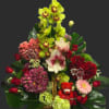 Mixed flower basket with orchids, roses, hydrangeas, and a small teddy bear