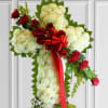 Cross-shaped floral spray with white blooms, red roses, and a red ribbon
