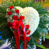 Heart-shaped white chrysanthemum arrangement with red roses and ribbon