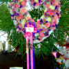 Heart-shaped floral wreath with pink, white, and purple flowers on a stand