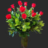 Red roses arranged in a clear glass vase with dense greenery