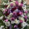 Large floral spray with pink roses, white chrysanthemums, and purple ribbon