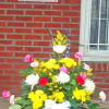 Colorful mixed flower arrangement in a white container with a ribbon