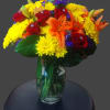 Bouquet of red roses, orange lilies, and yellow mums in a glass vase