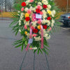 Large standing floral wreath with red, pink, and white flowers on an easel