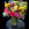 Colorful mixed bouquet in a glass vase on a stool