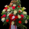 Large mixed flower arrangement in a white vase with a red ribbon