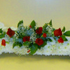 White floral arrangement shaped like a bone with red roses in the center