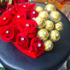 Red roses arranged with gold-wrapped chocolates in a heart-shaped box