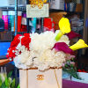 Flower arrangement with red roses, white carnations, and yellow calla lilies on a chocolate box