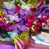 Purple orchids and pink calla lilies in a glass vase with butterfly picks
