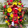Large standing floral spray with red roses and yellow lilies on a red ribboned easel