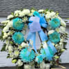 Large white and turquoise funeral wreath with blue ribbons