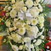 Large white funeral wreath with roses, chrysanthemums, and lilies