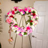 Heart-shaped floral wreath on a stand with pink, white, and red flowers