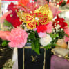 Mixed pink and red flower arrangement in a black box with a gold butterfly