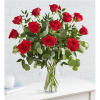Red roses arranged in a clear glass vase with greenery