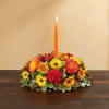 Low floral centerpiece with an orange candle in the middle