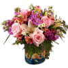 Pink roses and mixed blooms arranged in a blue glass vase
