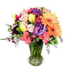 Colorful mixed bouquet in a clear glass vase with gerbera daisies, roses, and tulips