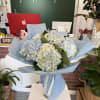 Bouquet of pale blue and white hydrangeas wrapped in light blue paper