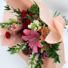 Bouquet of pink lilies, red carnations, and peach roses wrapped in blush paper
