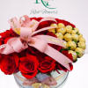 Red roses and gold-wrapped chocolates in a round glass box with pink ribbon