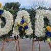 Three large white floral wreaths on wooden easels with blue and yellow roses
