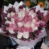 Bouquet of pink and white roses with purple flowers wrapped in pale paper