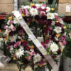 Large floral funeral wreath with pink, white, yellow, and burgundy flowers