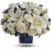 White lilies and roses arranged in a blue glass vase