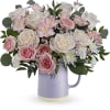 Pink and white roses arranged in a lavender pitcher vase