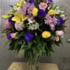 Mixed bouquet of lilies, roses, and daisies in a clear glass vase