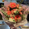 Peach bouquet with gerbera daisies and roses wrapped in pink paper